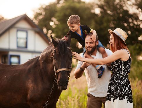 glückliche junge Familie streichelt ein Pferd